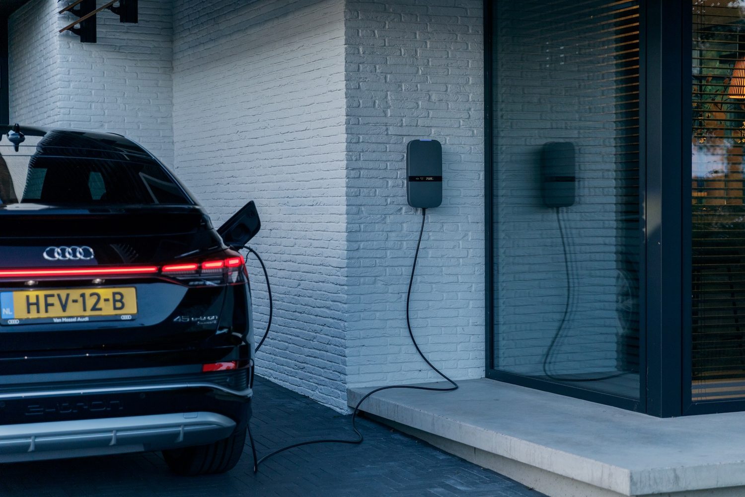 Peblar-laadpaal aan de gevel terwijl een elektrische auto laadt